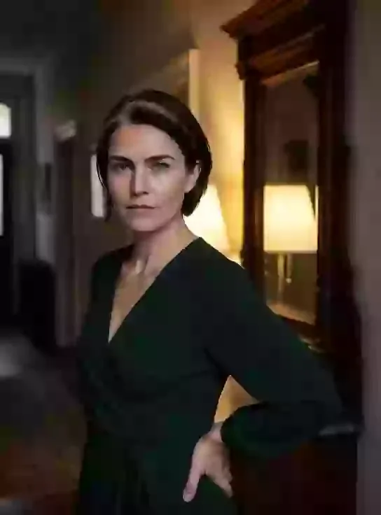 Helena, an adult AI character, standing in a dark green blouse in a softly lit room