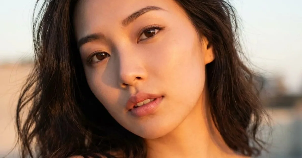 Close-up portrait of a dark-haired woman looking into the camera in warm evening light
