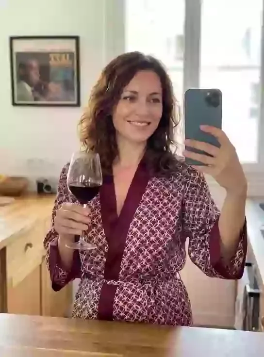 Claire, an adult AI character, taking a mirror selfie in a patterned robe with a glass of red wine